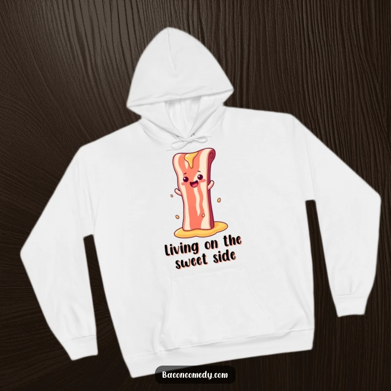 Funny hoodie with a happy bacon strip sliding down a syrup waterfall, radiating playful and sweet vibes.